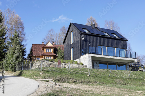 HUBA, POLAND - MARCH 28, 2024: .Two houses on the mountainside - one is historic and the other is modern, recently built.
