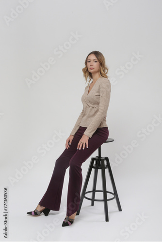 Serie of studio photos of young female model wearing basic flared purple trousers and knitted beige shirt, fall winter fashion collection