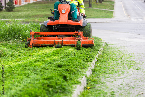 Worker mowing grass with ride-on lawn mower