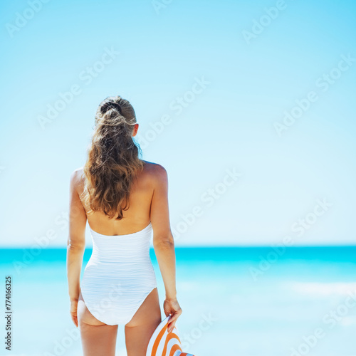 Happy young woman with hat on beach. rear view