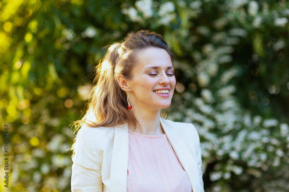 smiling modern woman in pink dress and white jacket in city smiling modern woman in pink dress and white jacket in city