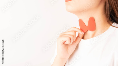 Female holding thyroid gland shape made from paper over her neck. Awareness of thyroid disorder includes goiter, hyperthyroid, hypothyroid, tumor or cancer. World Thyroid Day concept. photo