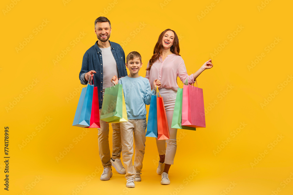 Family with shopping bags on yellow background
