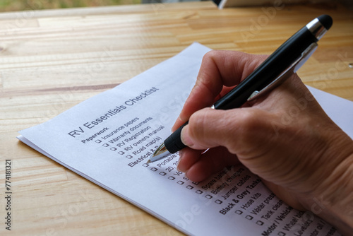 Hand holding a pen checking off boxes on RV Essentials Checklist