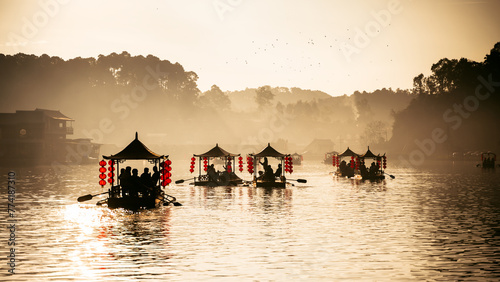 silhouette sailing chinese boat on lake in Ban Rak Thai village at sunrise photo