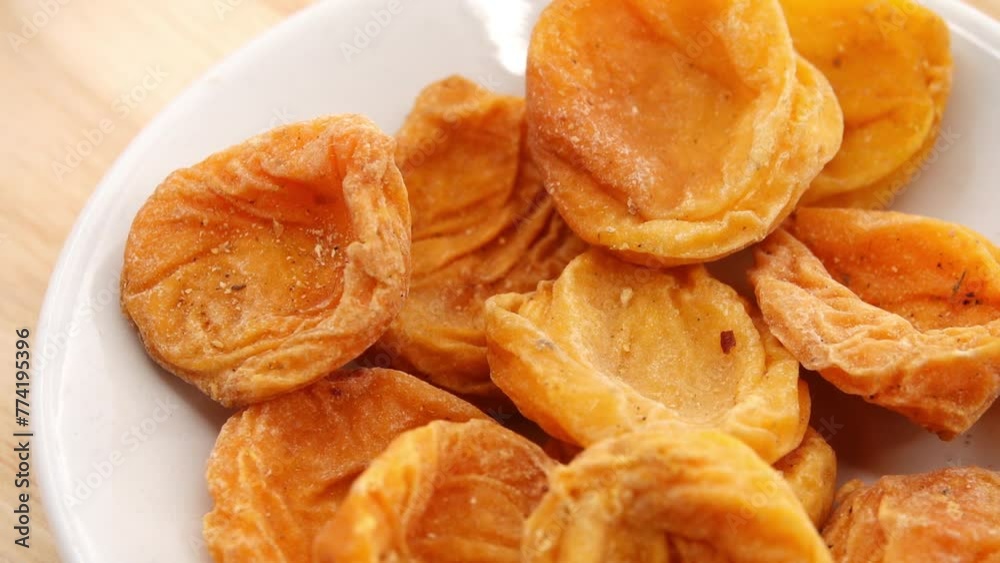 Gyration Yellow orange dried apricots on a white plate on a wooden table. Gyration Yellow orange dried apricots on a white plate on a wooden table.
