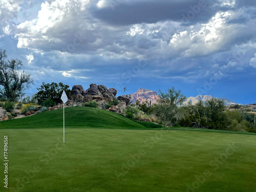 A putting green with a stormy desert background.