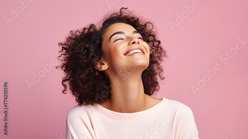 Portrait of a young happy woman throwing her head up and closing her eyes in pleasure on a pink isolated background. The concept of happiness, bliss, inner harmony and enjoyment of life