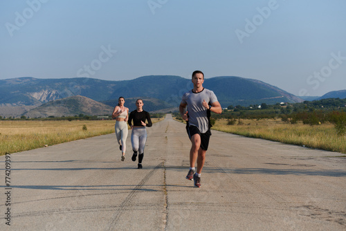 A group of friends maintains a healthy lifestyle by running outdoors on a sunny day, bonding over fitness and enjoying the energizing effects of exercise and nature © .shock
