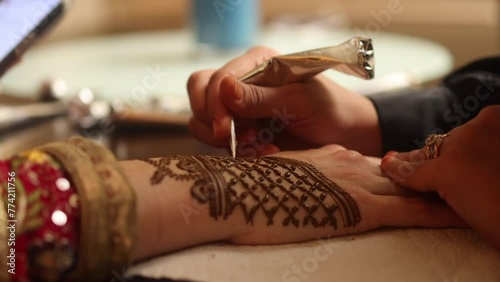 aplicando un tatuaje hindu en las manos de una mujer photo
