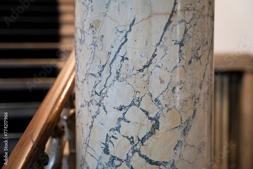 Closeup details on marble pillar with marble stairways in background.