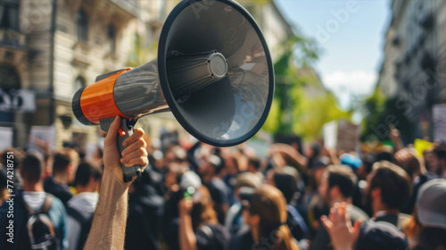 Crowd protesting in the street with focus on loud speaker in hand © brillianata