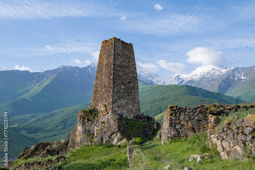 Ancient Ossetian defensive tower against the background of the Caucasian mountains on a sunny June morning. Tsmiti. North Ossetia-Alania, Russia photo