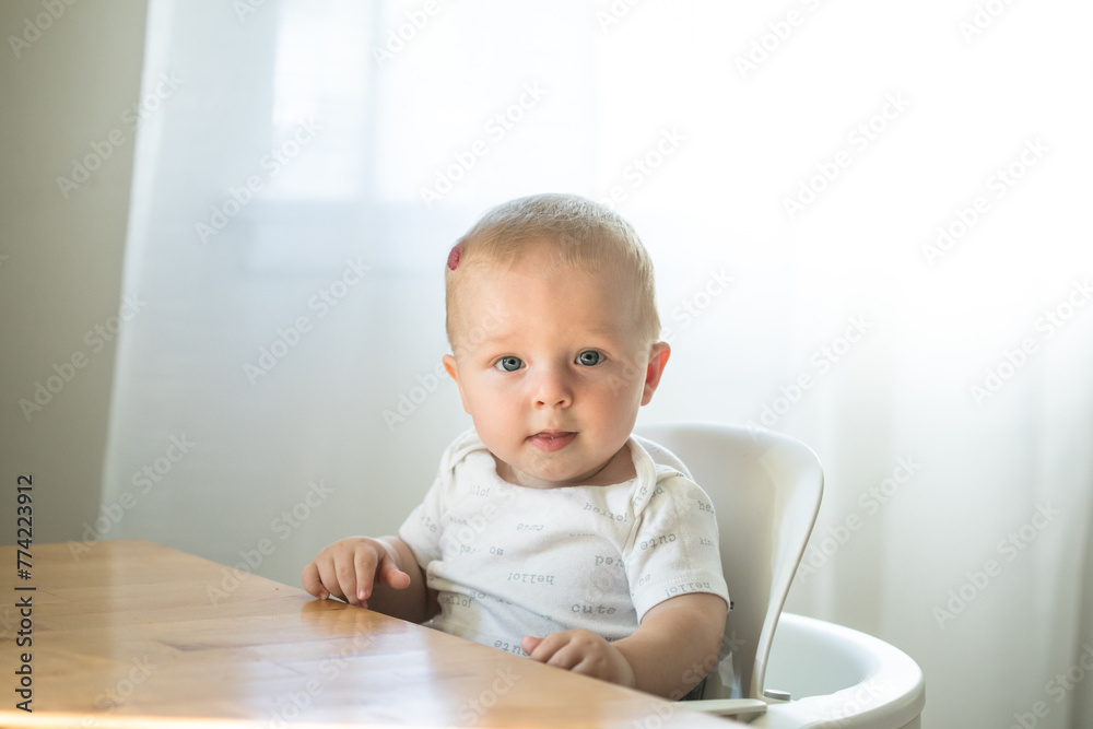 Baby boy sitting in high chair ready for eating Baby boy sitting in high chair ready for eating