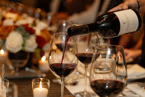 A sommelier expertly pours red wine from a elegant bottle into a crystal wine glass during a wine pairing event