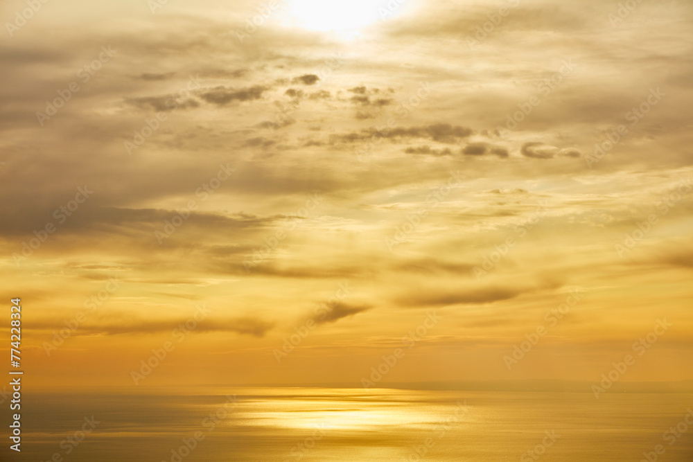 雲の隙間から見える夕日と海