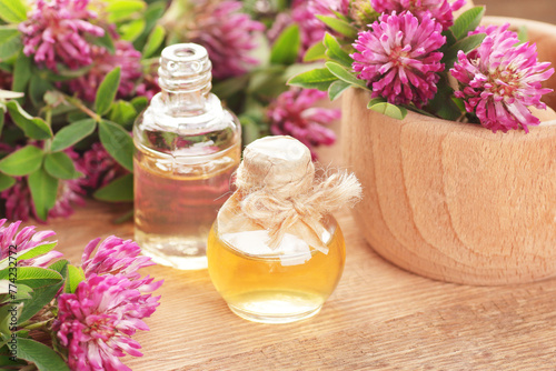 Red clover extract or oil with leaves and flowers on rustic background, closeup, remedy for menopause, source of estrogen, used in cosmetics, spa, face and hair beauty