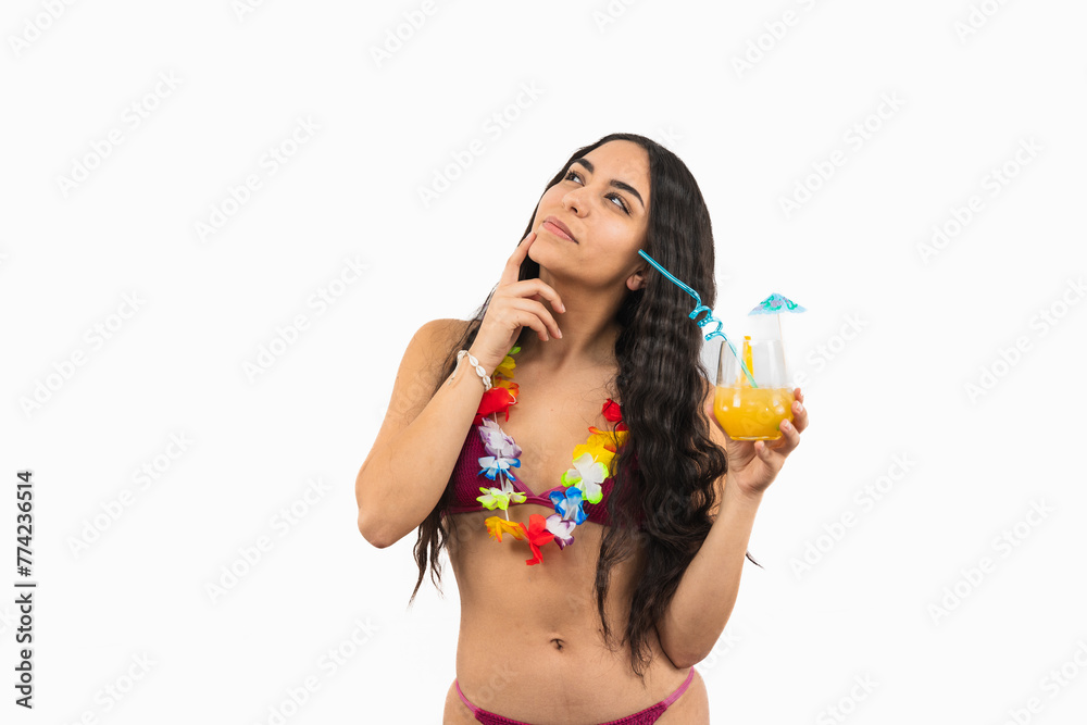 Pensive brunette Latin woman in bikini holding a orange soda with hand on face on white background Pensive brunette Latin woman in bikini holding a orange soda with hand on face on white background