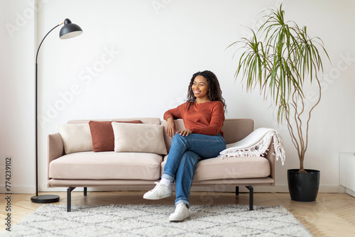 Relaxing Afternoon at Home: Smiling Black Woman on Sofa in Living Room