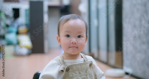 A baby toddler child is looking at the camera with a smile on its face and spit saliva from her mouth