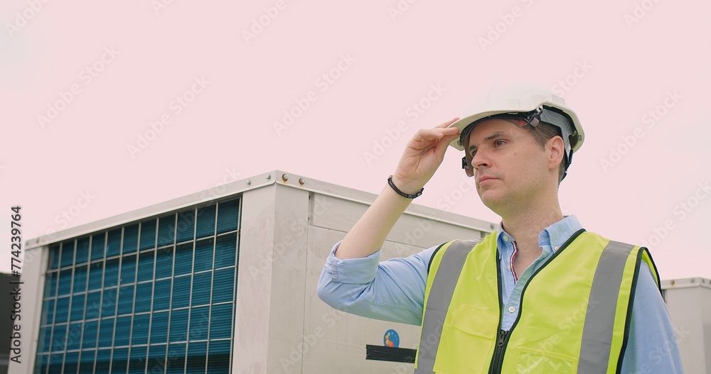A focused contemplative engineer worker in a white hard hat and reflective safety vest looking into the distance at a construction site near industrial equipment A focused contemplative engineer worker in a white hard hat and reflective safety vest looking into the distance at a construction site near industrial equipment