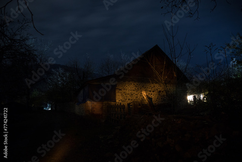 Old house with a Ghost in the forest at misty night or Night scene with House under moon. Old mystic building in dead tree forest.