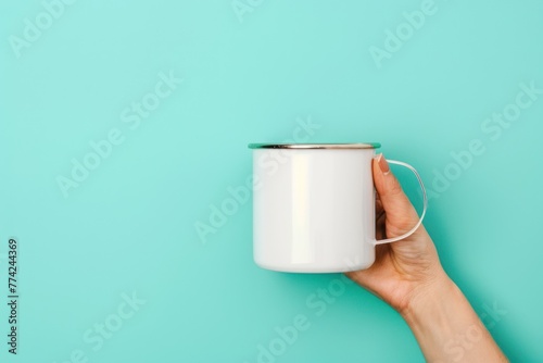 Woman's hand holding metal white thermal mug isolated on light turquoise background with space for text photo