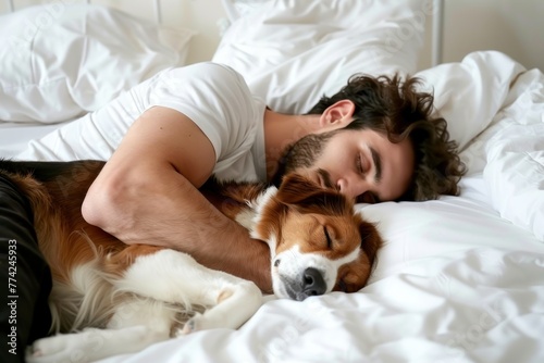Young man and dog sleeping together in white bed at home