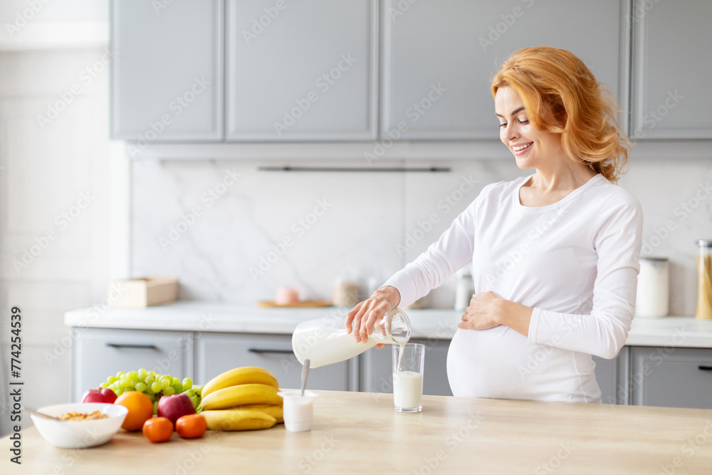 Pregnant woman pouring milk in kitchen