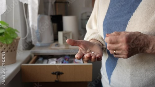 Close up of old woman hands holding medicine pills and trying to remember how much she took of them. Alzheimer, elderly woman counting her drugs.
