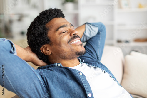 Black Man Relaxing on Couch With Hands Behind Head