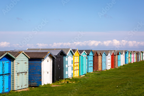 Beach huts along the Essex coast, Image shows a range of different colours and styles of beach huts on a warm spring day with slight cloud and blue sky photo