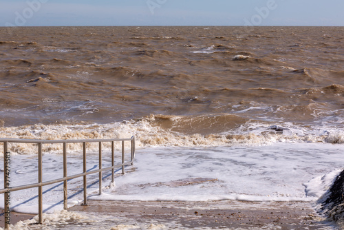 Beach access ramp to a part of Dovercourt beach during a rough high tide or spring tide, Image shows the large waves completely covering the sandy beaches  photo