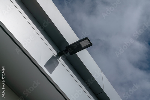 modern led street lamp on new construction with flat roof and metal facade, roof of a house, building with galvanized steel roof and cornice front. roof flashing