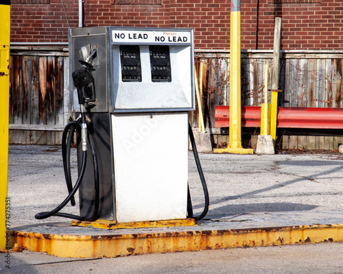 An unidentified old white 1960's style gas pump on a rusty gas station island