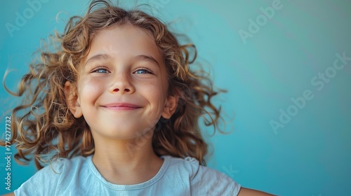 Young Girl Smiling Happily Against Teal Background - blank copy space photo