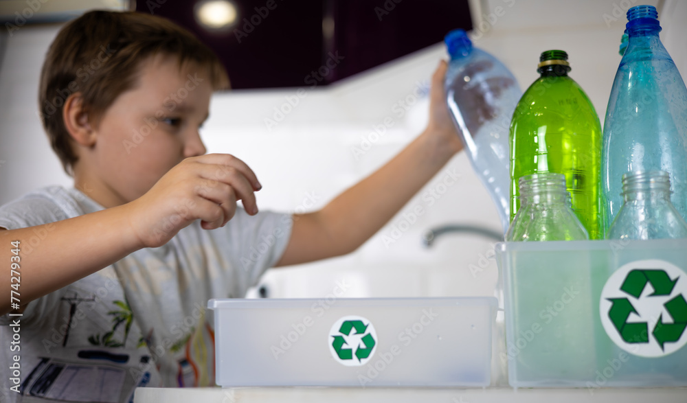 A child stacks plastic bottles in boxes with a recycling sign. Parents teach their child to sort garbage and recycle it. The concept is eco-friendly, caring for nature. A child stacks plastic bottles in boxes with a recycling sign. Parents teach their child to sort garbage and recycle it. The concept is eco-friendly, caring for nature.