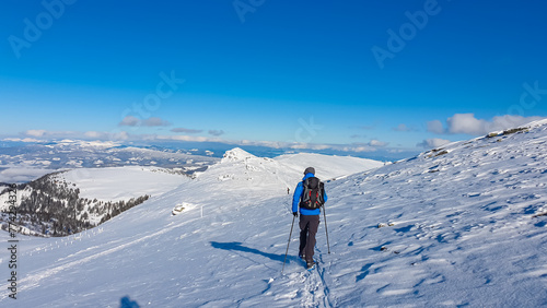Man in snowshoes on snow covered mountains of Kor Alps, Lavanttal Alps, Carinthia Styria, Austria. Winter wonderland in Austrian Alps. Ski touring and snow shoe tourism. Tranquil serene atmosphere