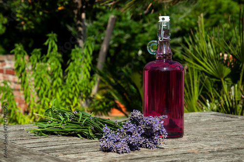 Home-made Lavender Syrup on an Old Wooden Table with a Bouquet of Lavender Flowers