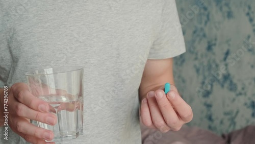 Man drinking a PrEP blue pill with glass of water. HIV prevention using Pre-Exposure Prophylaxis medicine. Men health. AIDS prevention concept photo