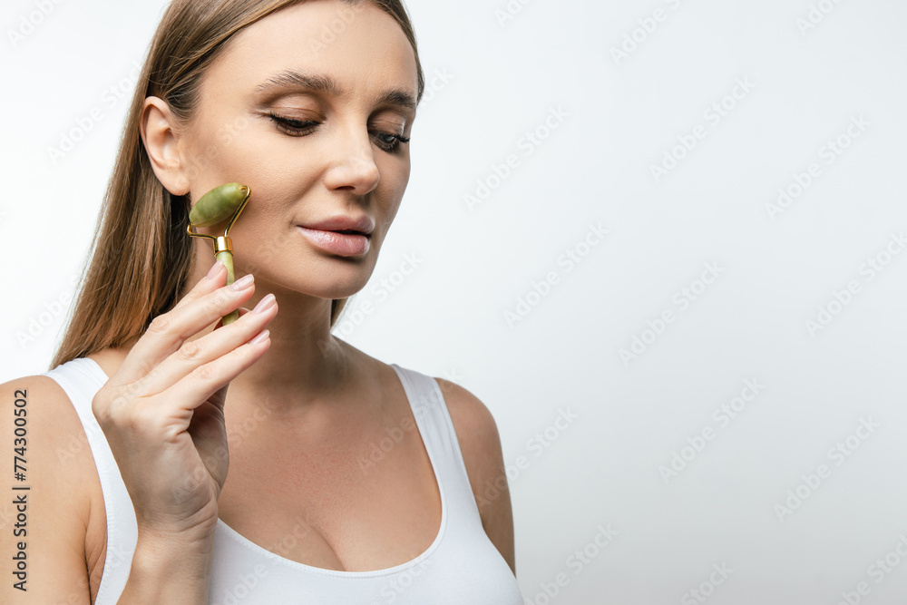 Blonde woman making face massage with a roller Blonde woman making face massage with a roller