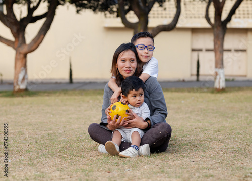 Hispanic mother hugging her children in a field - son hugging her mother in a park - Mother's Day celebration. Single mother with her two children happy