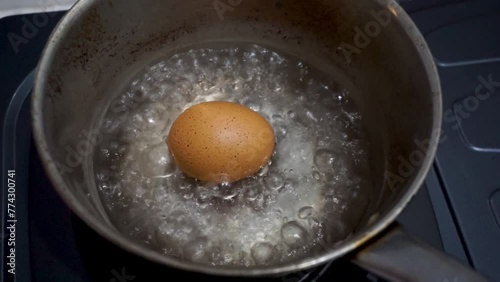 Chicken egg boiling in pan. Close up of bubbling water while boiling eggs in stainless pan