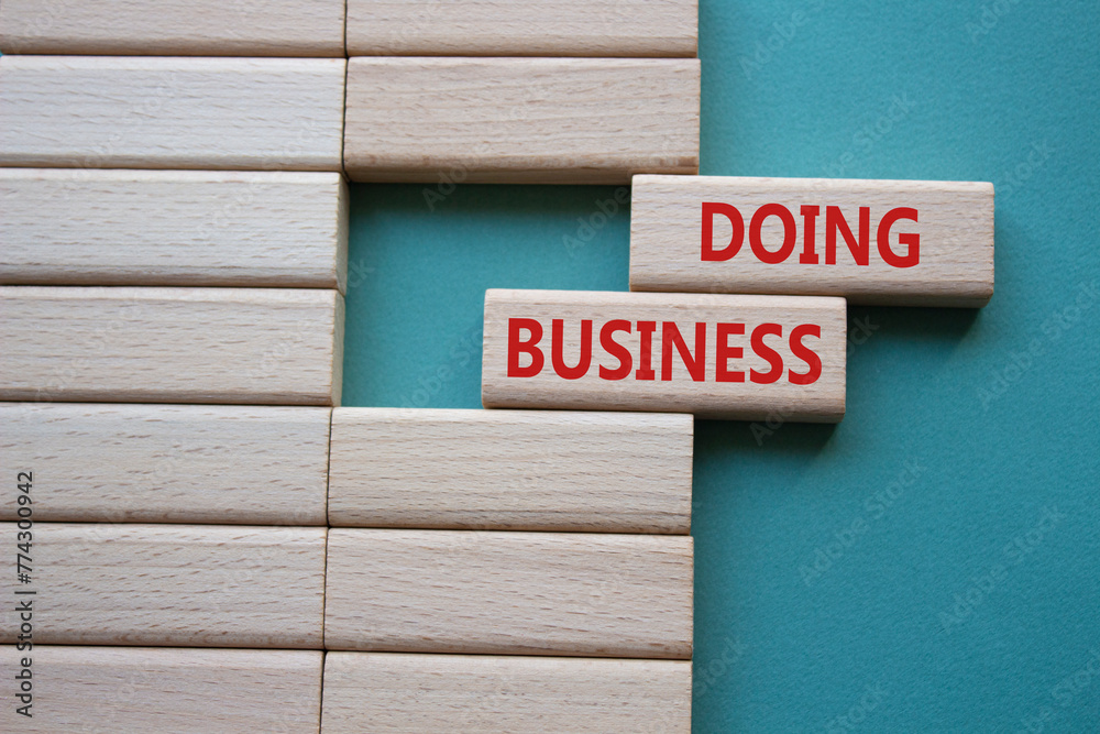 Doing Business symbol. Concept word Doing Business on wooden blocks. Beautiful grey green background. Business and Doing Business concept. Copy space Doing Business symbol. Concept word Doing Business on wooden blocks. Beautiful grey green background. Business and Doing Business concept. Copy space