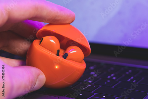 Box with Orange Wireless Bluetooth Earphones in man's hands. Modern Stereo Headphones, Sports Headset.