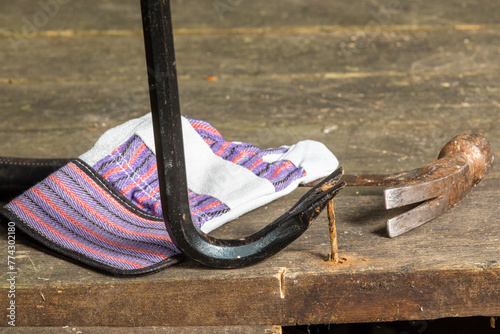 Photos A worker's gloved hand using a pry bar to pull a rusty nail in a renovation cons