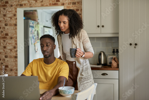 Young multiethnic couple using a laptop in their kitchen in the morning