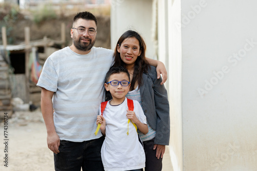 Portrait of Hispanic family - Latino parents with their son who goes to school with his backpack - parents proud of their son who is going to study