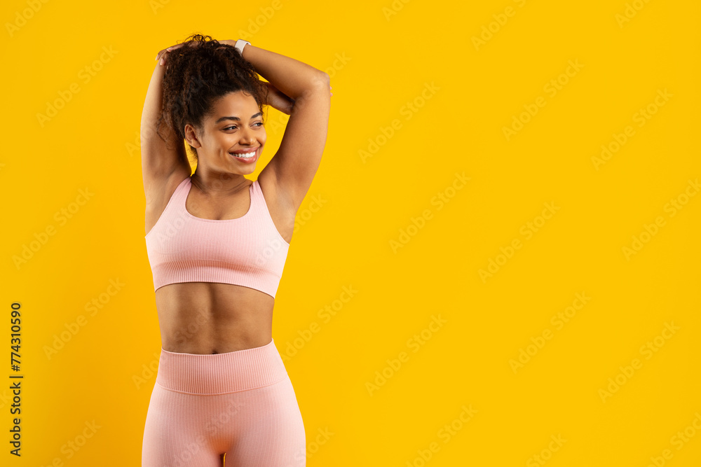 Fototapeta premium Smiling african american woman in workout gear on yellow
