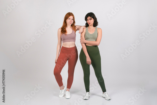Two young women in sportswear posing together on white background horizontal photography